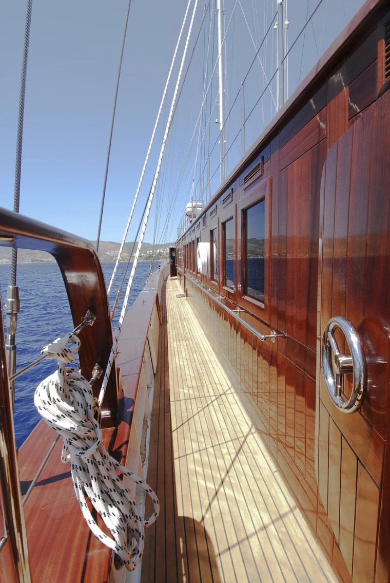 Teak side deck and varnished woodwork aboard a sailing yacht.