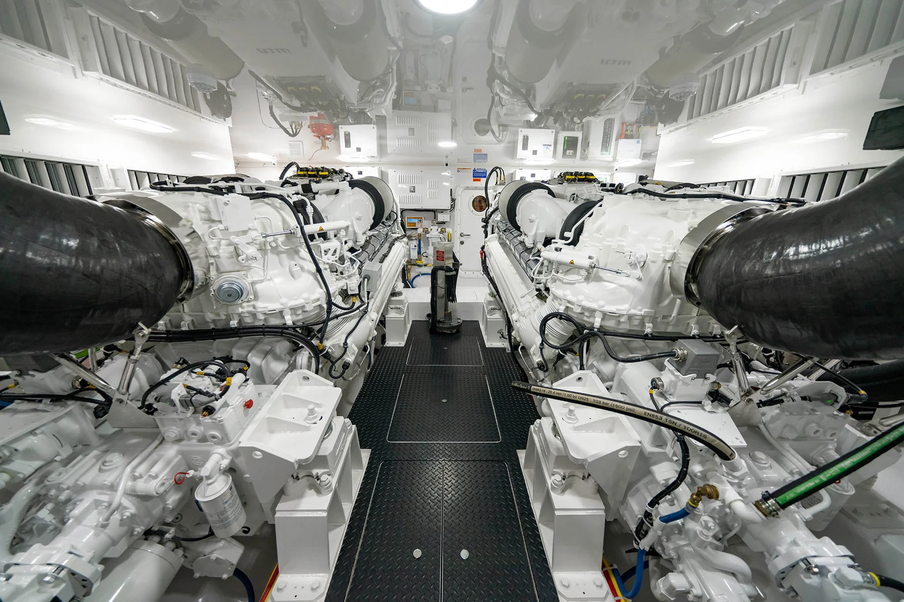 Twin inboard engines and associated machinery in a yacht engine room.