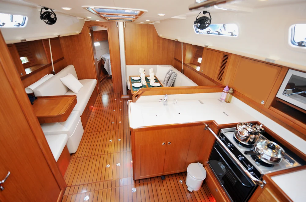 Sailing yacht interior showing the salon, galley, and passage to the forward cabin.